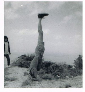 Man standing on his head on top a mountain